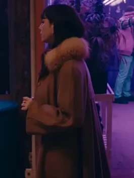 Side profile of Susie Glass in The Gentlemen 2024 wearing the iconic long Kaya Scodelario brown fur coat in a dark setting.