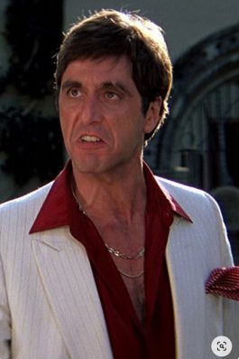 Full shot of Scarface in white suit descending stairs, showing the iconic 70s suit style.