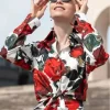 Lily Collins as Emily Cooper in Emily in Paris Season 5 wearing a vibrant rose print long-sleeve shirt.
