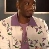 Samuel Arnold as Julien in Emily in Paris Season 5 wearing a vibrant purple cardigan with floral embroidery.