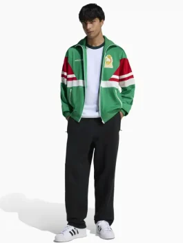 This view helps you judge the overall fit and length. The green Mexico 1986 track jacket is easy to layer over a tee or under a light jacket. Wear it with sneakers for a clean casual look. Choose your usual size for a regular fit, or size up for a relaxed feel.