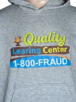 Flat studio layout of the garment-dyed grey Quality Learning Center Hoodie highlighting the texture of the baby blue embroidered lettering and cartoon rabbit chest patch.