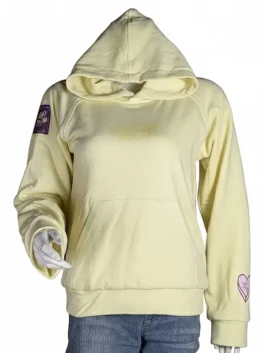 A smiling young woman wearing a light grey Salish Matter "Sincerely Yours" hoodie with yellow cursive embroidery.