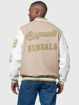 Back view of a tan varsity jacket with large gold embroidery reading "Cincinnati Since 1968 Bengals" across the wool body with white faux-leather sleeves.