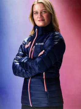 A woman posing in a navy Team USA puffer jacket with arms crossed, highlighting the white and red zippered chest pocket.