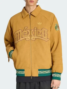 A person wearing the tan Adidas Mexico jacket, showing the embroidered "México" chest text, green ribbed cuffs, and gold Trefoil logo.