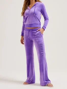 Front view of a purple velour Juicy Couture tracksuit, featuring a zip-up hoodie and matching flared pants with a vertical "Juicy" rhinestone logo on the leg.