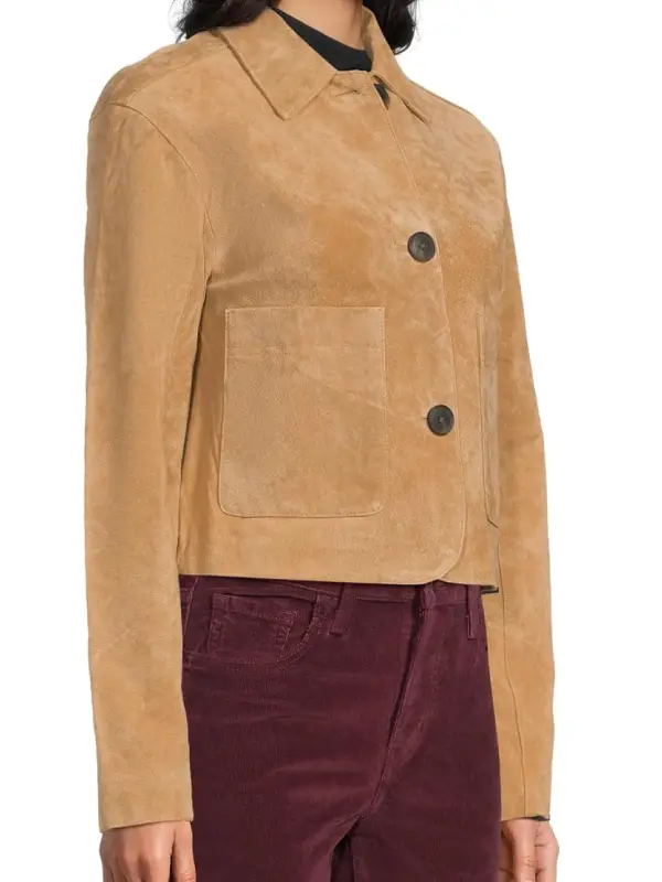 Close-up of large patch pockets and dark contrast buttons on a tan suede leather jacket.
