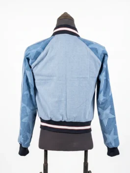Rear view of the light blue Adidas Denim Graphic Varsity Bomber Jacket on a mannequin, featuring dark contrast sleeves covered in faded star graphics.