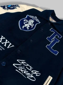 Detailed front close-up of Team Liquid varsity jacket with patches, button closure, and embroidered graphics