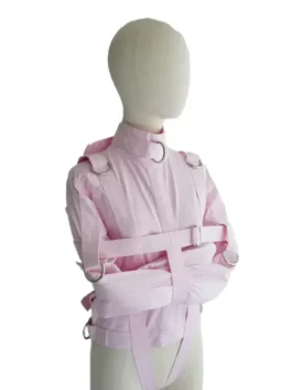 Three-quarter angled view of the baby pink ABDL straight jacket highlighting the sleeve restraints and side hardware.