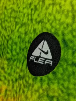 Extreme Macro Detail of Circular Embroidered Dark Chest Patch Attached to Vibrant Green Background