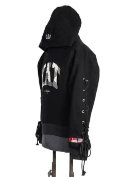 Three-quarter angled profile view of a cropped black fleece hoodie highlighting the camouflage applique chest patch and side sleeve lace-up cords.