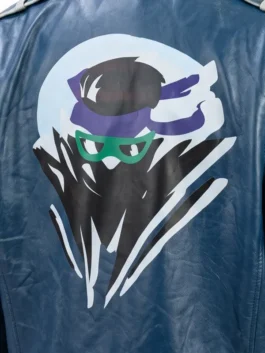 Close-up of the back graphic on the Mortal Kombat 2 Johnny Cage blue jacket, featuring a stylized ninja character art design with a purple headband and green glasses.