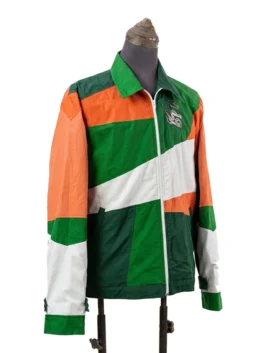 Right-angled view of a green, orange, and white geometric track jacket showcasing the clean lines of the white zipper closure and the curved chest emblem.