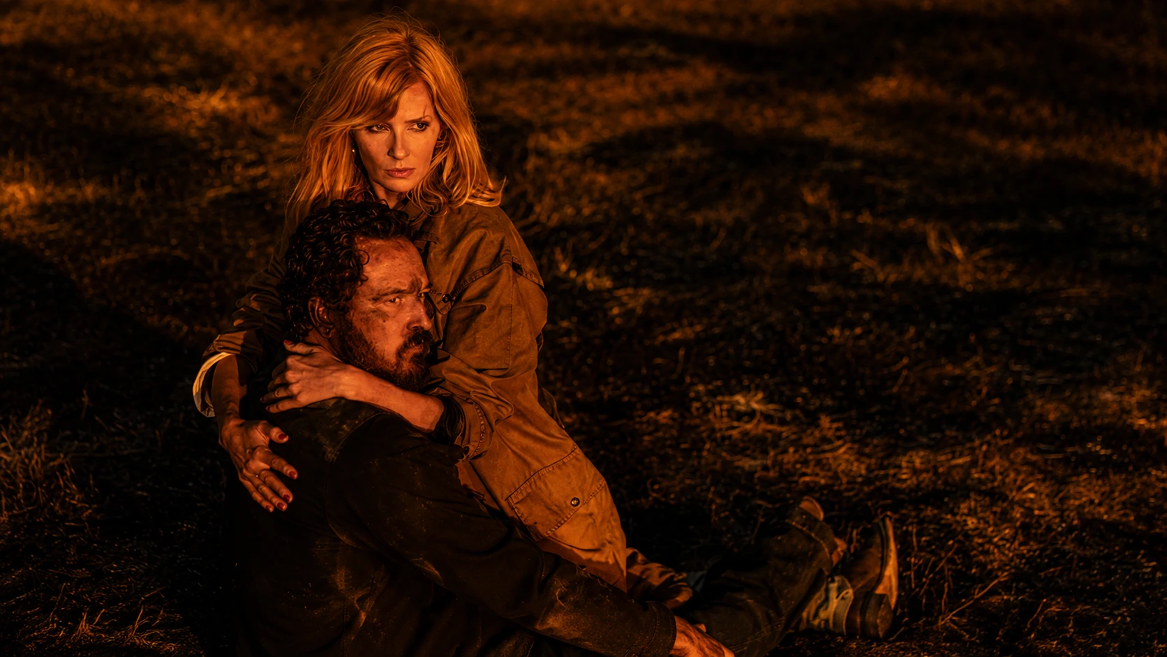Kelly Reilly as Beth Dutton holding injured Rip Wheeler Cole Hauser on scorched ground at night in dramatic scene from Dutton Ranch Season 1 2026 Paramount Plus