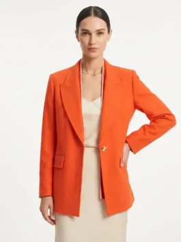 Model wearing the vibrant orange Princess Leonor Orange Suit featuring a structured lapel collar and tailored suiting fabric.